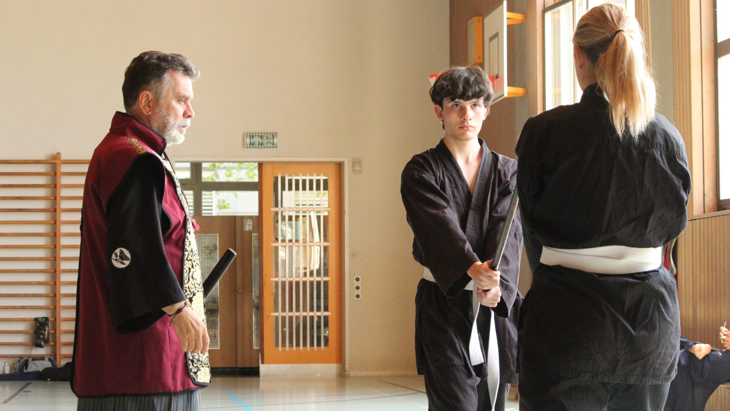 Fotografía de Alice Pedersen. Dos practicantes de la escuela WA REI RYU de Suiza vajo la mirada atenta del Maestro (SenSei) Francisco Royo. En la indumentaria vemos que visten Obis estrechos